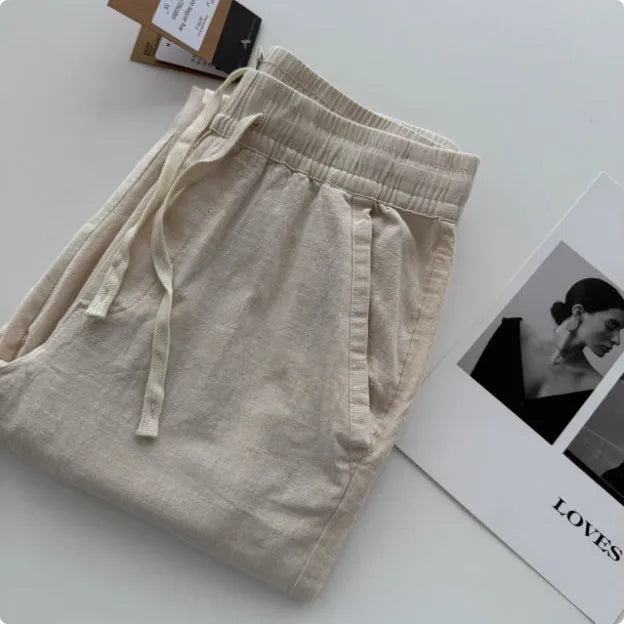 Man wearing beige loose straight leg casual trousers with a drawstring waistband.