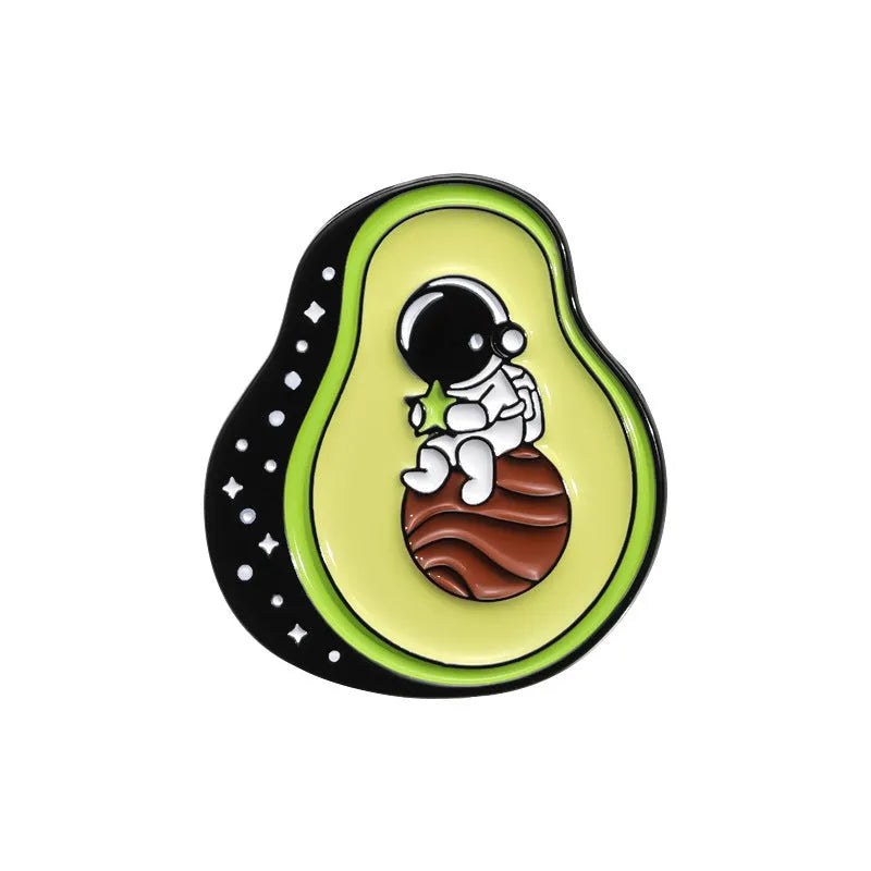 Colourful cartoon fruit and letter design metal brooch on a fabric background.