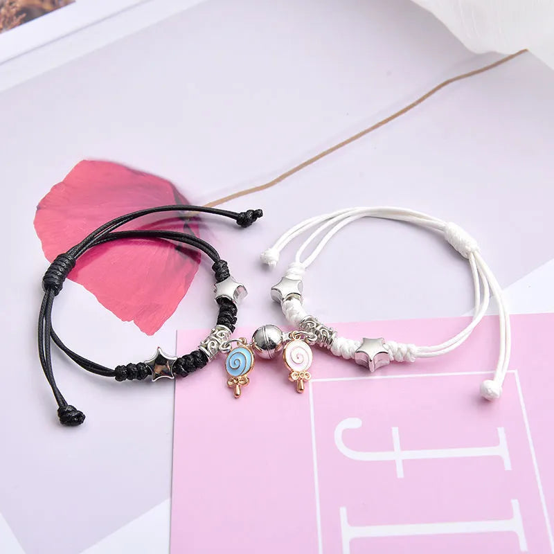 Pair of magnetic suction bracelets with alloy charms in various love and friendship themed designs on a wrist.