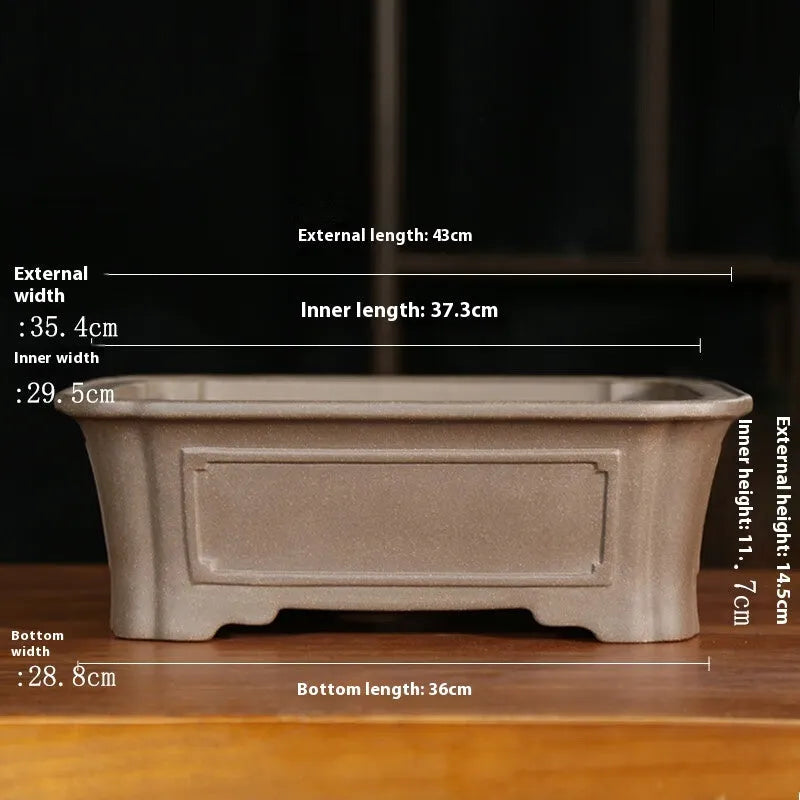 Rectangular antique purple sand bonsai planter with corner-cut design on floor.