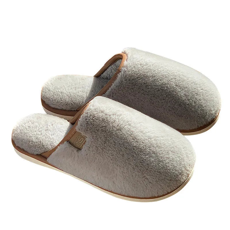 Solid colour PVC plush winter house slippers on a wooden floor.