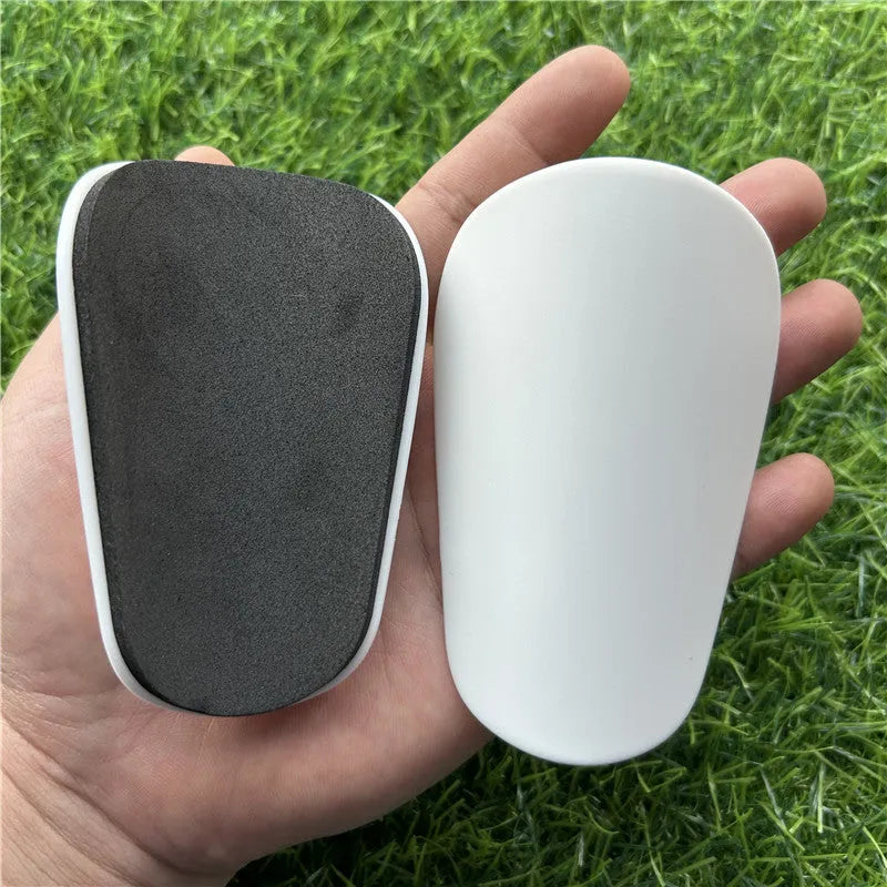 Extra small mini football shin guards in black and white colours measuring 8cm by 5cm