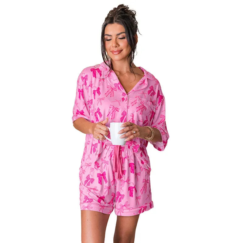 Women's pink polyester pyjama set with bow print detail showing top and matching trousers