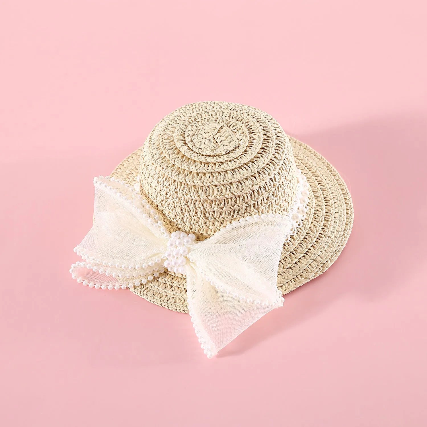 Cat wearing a woven straw hat with a pearl bow decoration in a princess style.