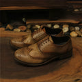 Light brown vintage engraved men's lace-up leather shoes with distressed finish and round toe.