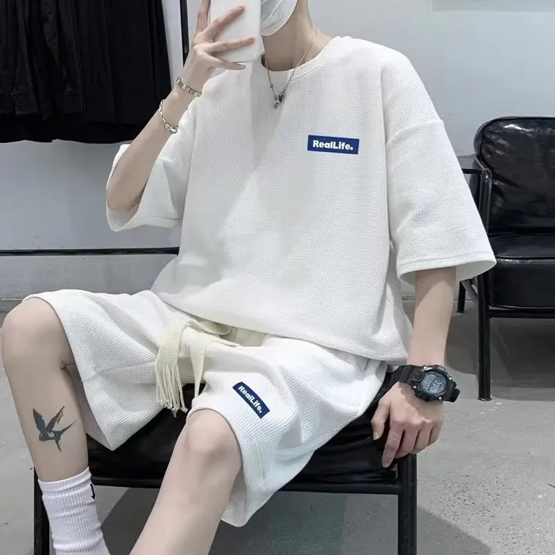 Man wearing a grey waffle-textured short sleeve top and matching shorts leisure set.
