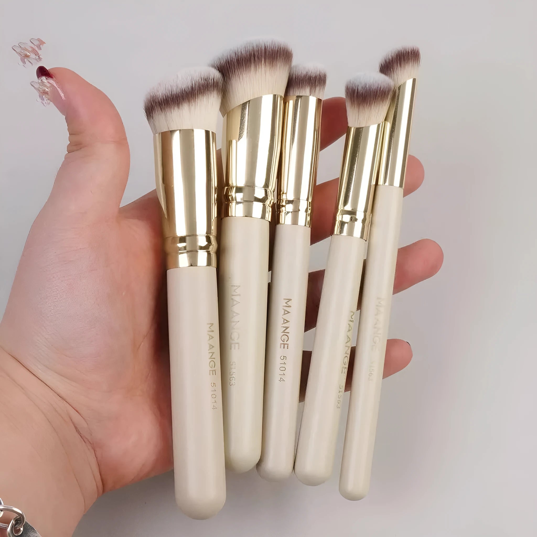 MAANGE five apricot coloured makeup brushes with angled blush brush on pink surface