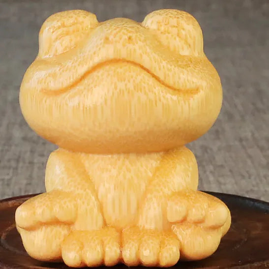 Solid bamboo carving of a cartoon smiling frog ornament, 5cm tall.