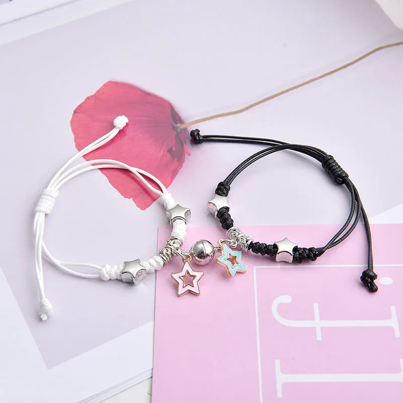 Pair of magnetic suction bracelets with alloy charms in various love and friendship themed designs on a wrist.