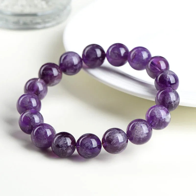 Natural Feather Amethyst crystal bracelet with Ruyi charm beads on a wrist.