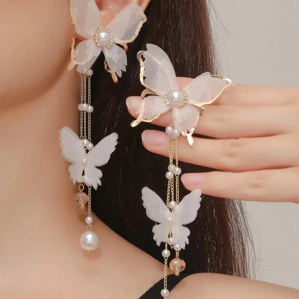 White butterfly-shaped drop earrings with pearl and rhinestone accents on a tassel lace design.