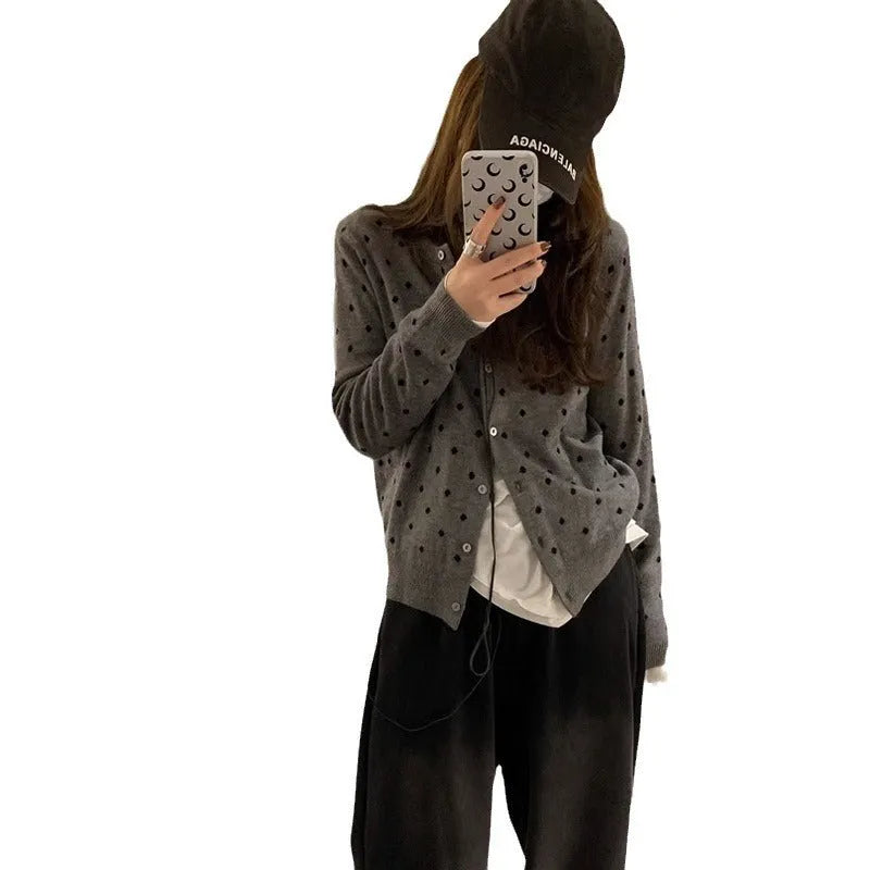 Women's grey dot pattern knitted cardigan with crochet flower details on sleeve.