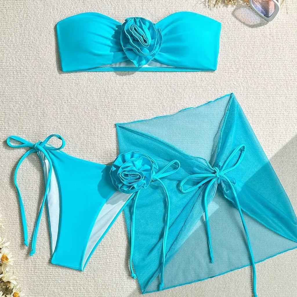 Women's pink swimsuit set with a large 3D flower tie, matching pants, and a separate skirt.
