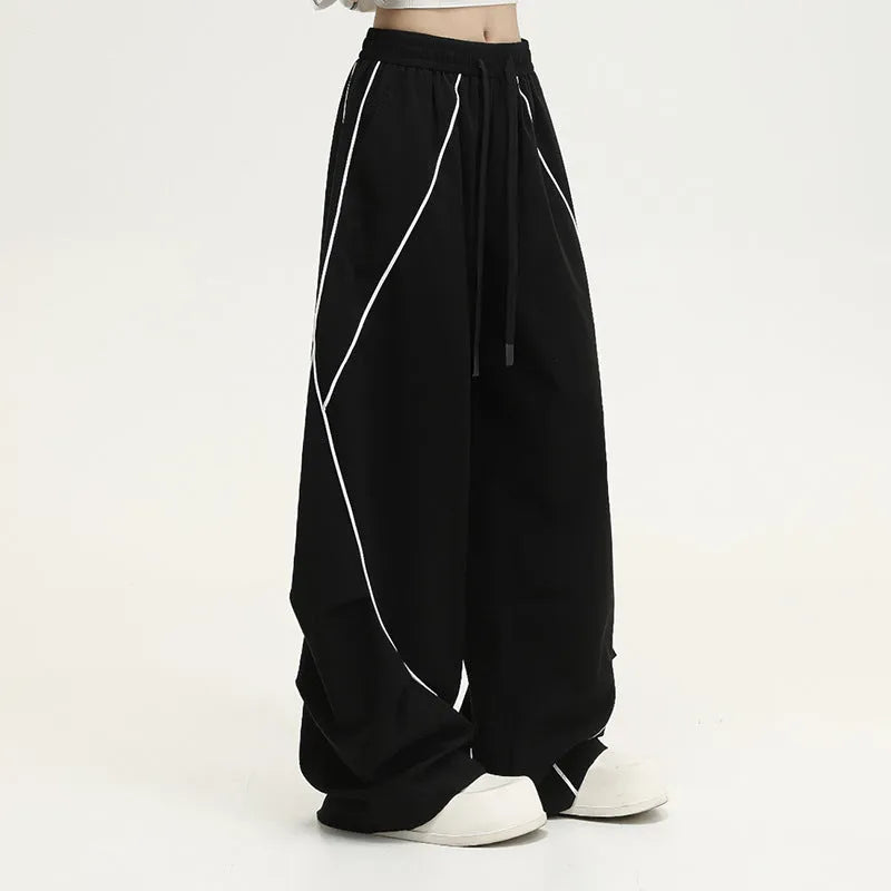 Black pleated wide-leg hip hop sports trousers on a hanger, showing loose fit and striped pattern.