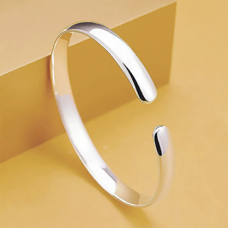 Glossy silver-plated copper bracelet with Ruyi and lucky cat charms on white background