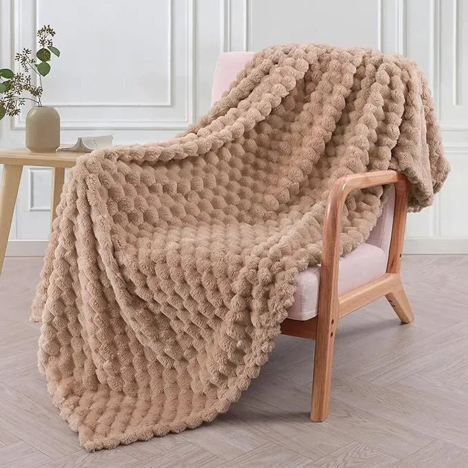 Soft camel-coloured plaid fleece blanket for children folded on a bed.