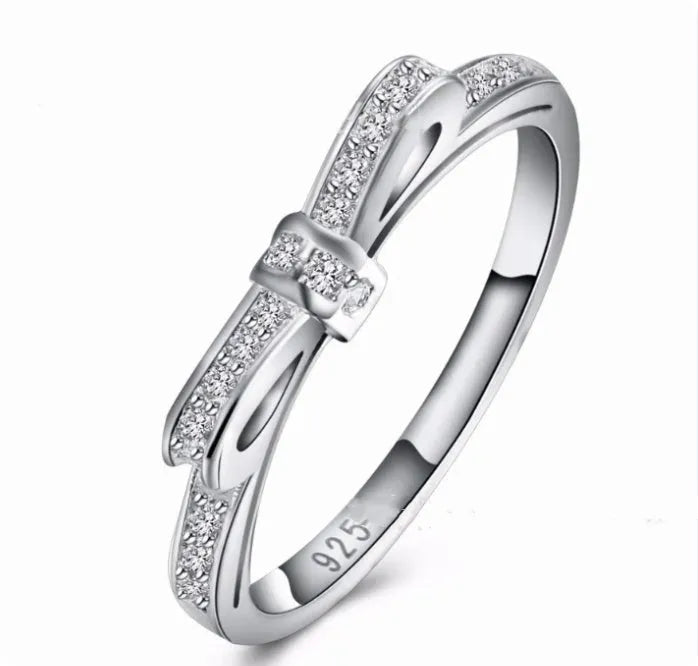 Silver bow-shaped ring with crystal rhinestones on finger