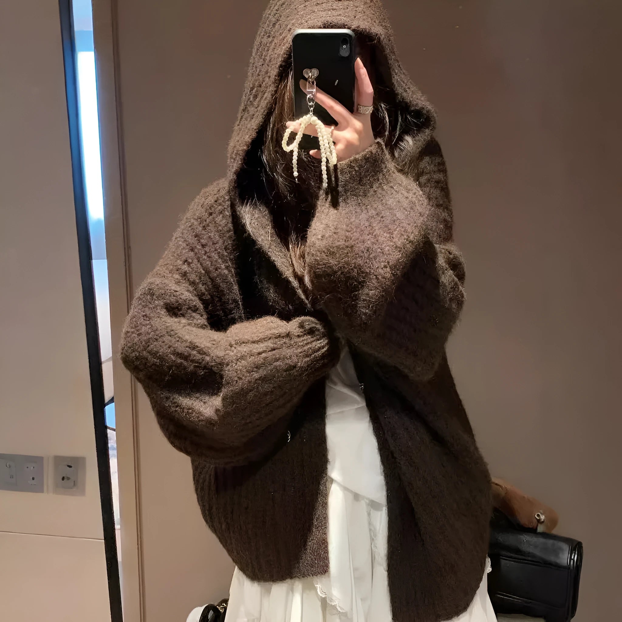 Woman wearing a loose-fit, chunky knit hooded cardigan in a macaron colour.