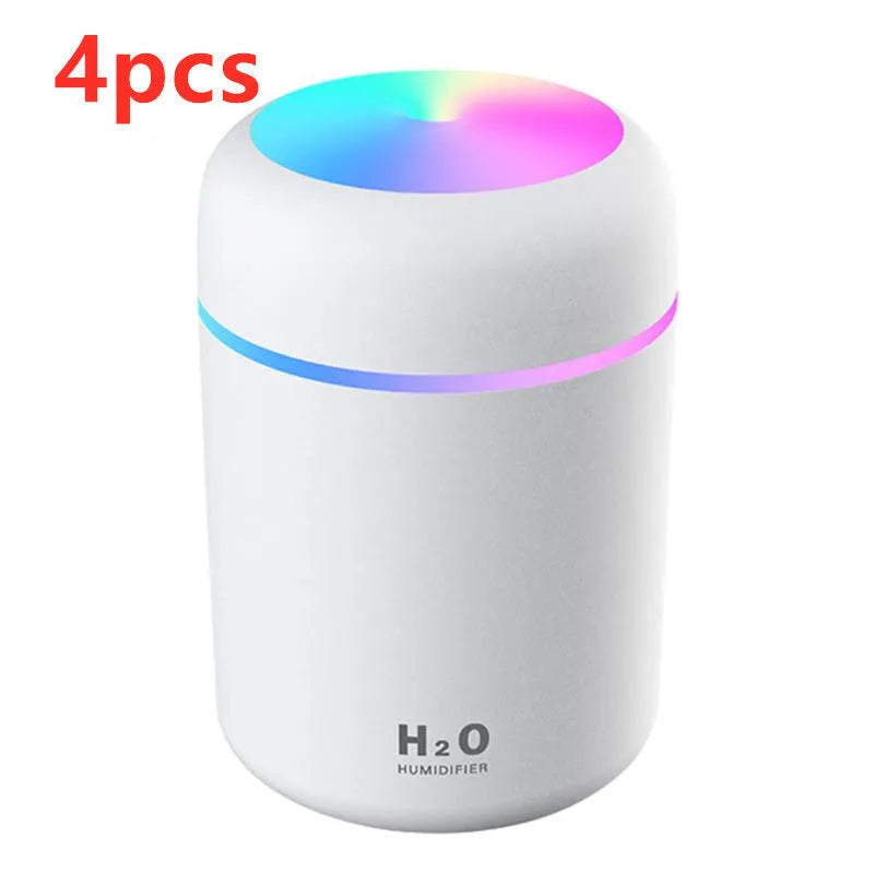 Pink USB desktop humidifier with LED lights and water tank on a wooden desk.