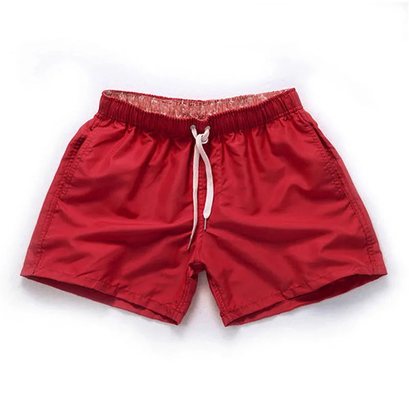 Men's black surf shorts made from polyester fabric with a straight leg opening, shown on a size chart.