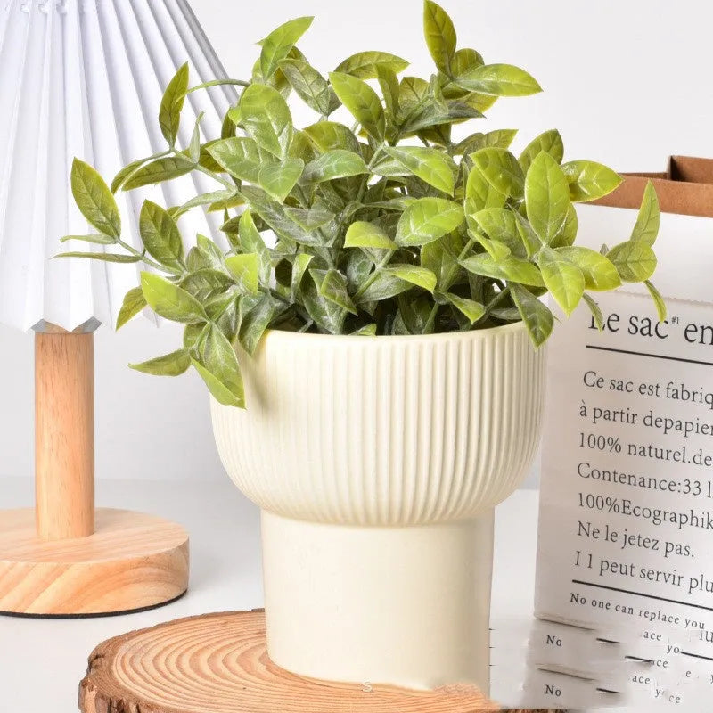 Matte yellow ceramic flower pot with a Roman column design on a table.