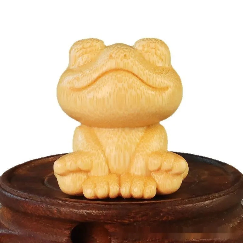 Solid bamboo carving of a cartoon smiling frog ornament, 5cm tall.
