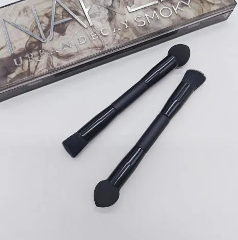Double-headed black makeup brush with a pointed concealer brush on one end and an angled sponge on the other.