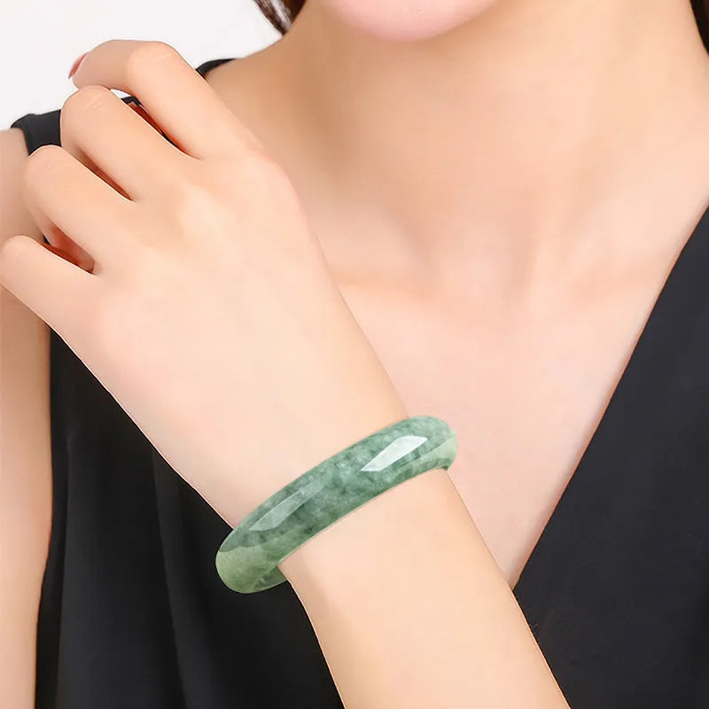 A simple deep pea green women's bracelet shown with a gift box and certificate.