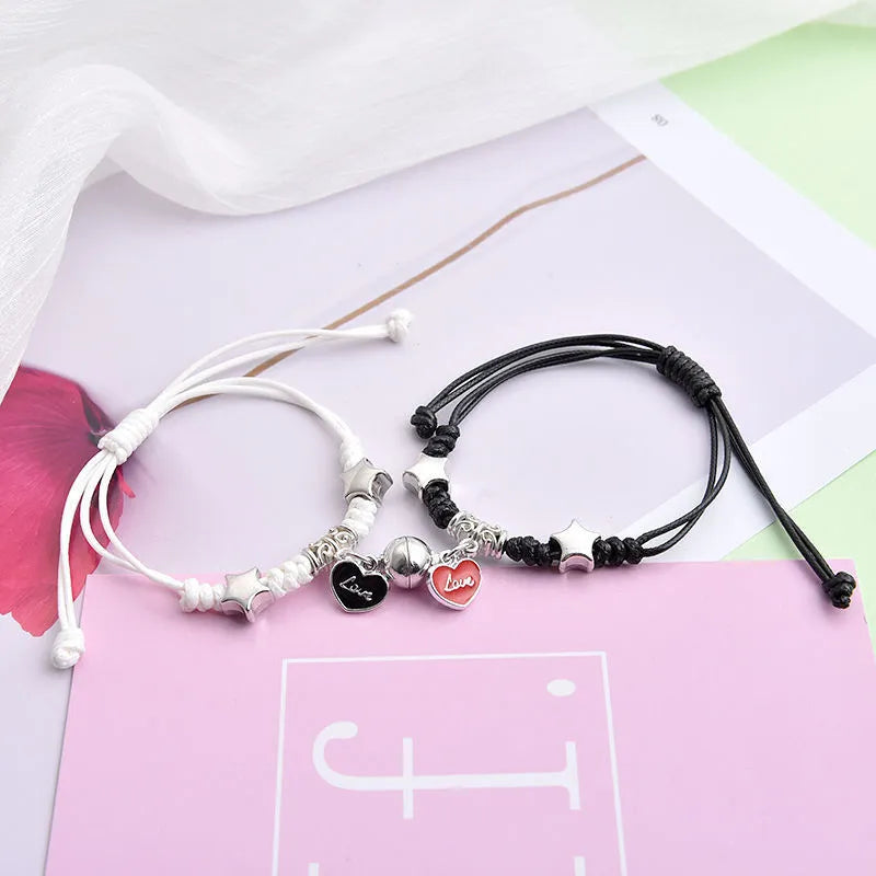 Pair of magnetic suction bracelets with alloy charms in various love and friendship themed designs on a wrist.