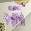 Women's pink swimsuit set with a large 3D flower tie, matching pants, and a separate skirt.