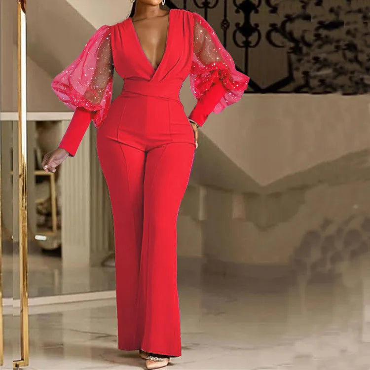 Red women's jumpsuit with mesh stitching on long sleeves, slim fit bodice, wide legs, and elastic waist.