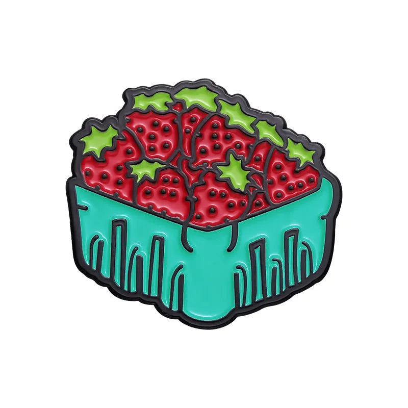 Colourful cartoon fruit and letter design metal brooch on a fabric background.