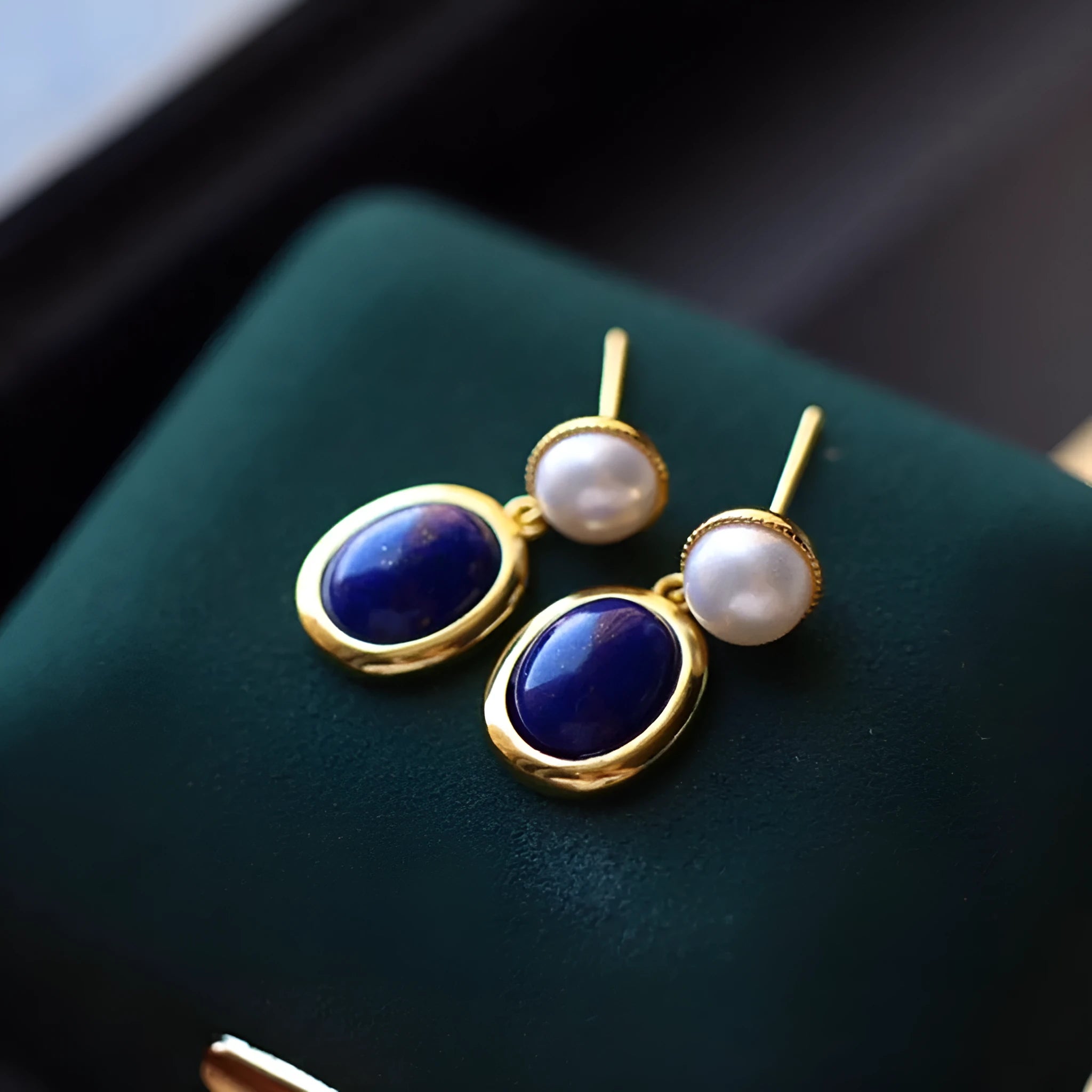 A pair of simple sterling silver drop earrings with a blue lapis lazuli pearl and auspicious patterns.