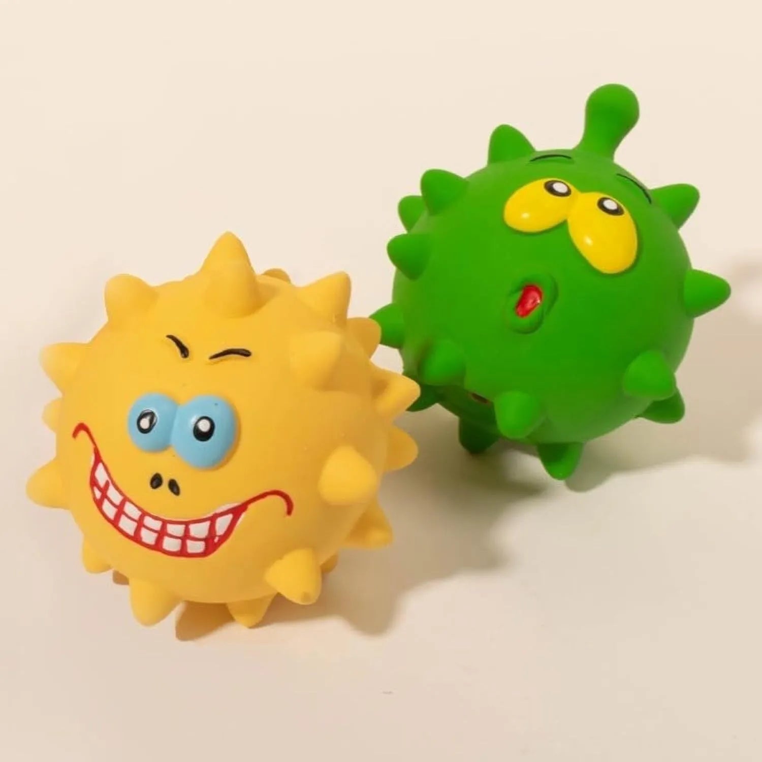 Set of four colourful latex squeaky dog balls with cute faces on bumpy textured surfaces