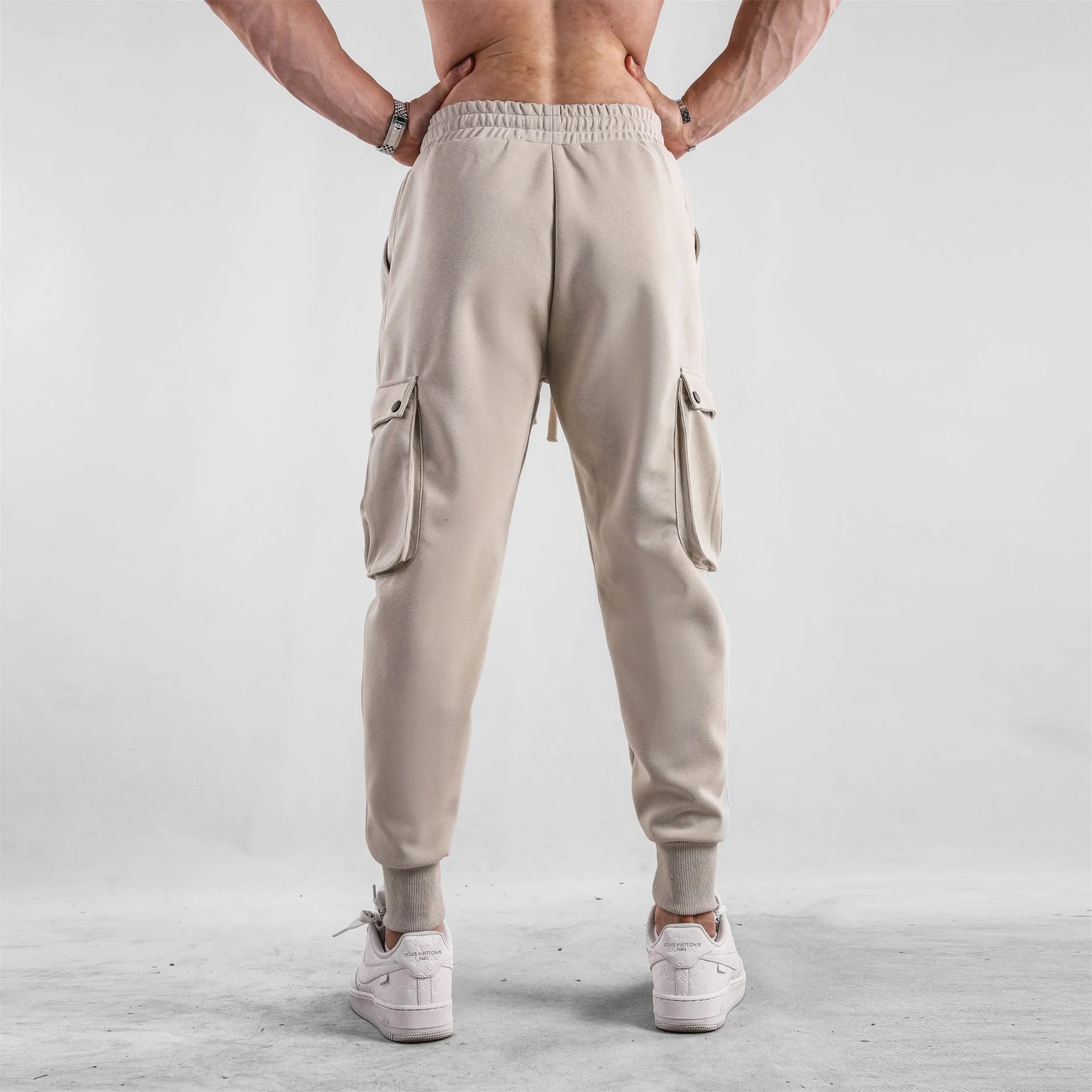 Men's loose-fit light grey cotton sports trousers with ankle tie and side pockets.