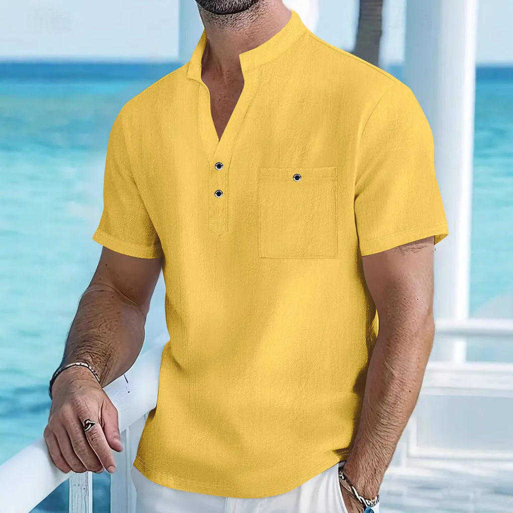 Man wearing a light-coloured, loose fit linen t-shirt with a stand collar and short sleeves.