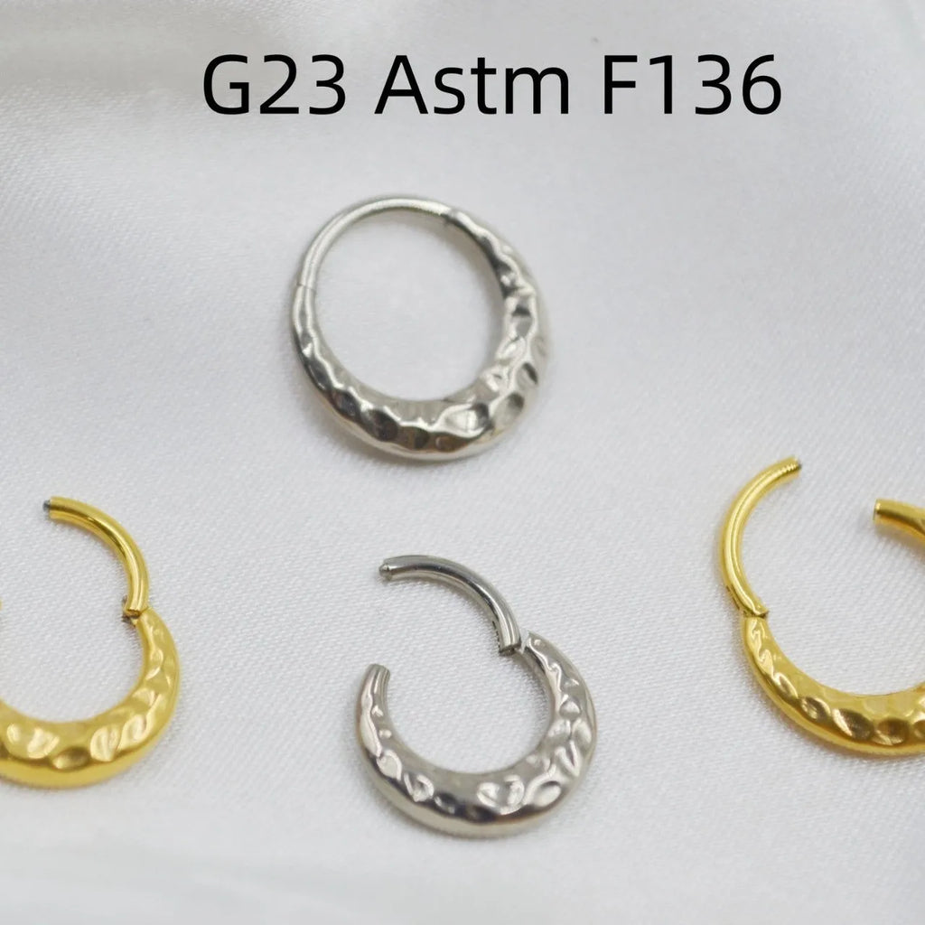 Close-up of a titanium concave-convex nose ring in gold finish, showing its textured profile and 1.2mm thickness.