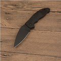 Portable folding fruit knife with black handle and silver 9CR13MOV blade on a wooden surface