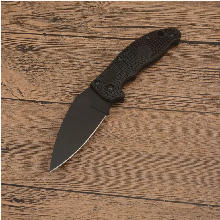 Portable folding fruit knife with black handle and silver 9CR13MOV blade on a wooden surface