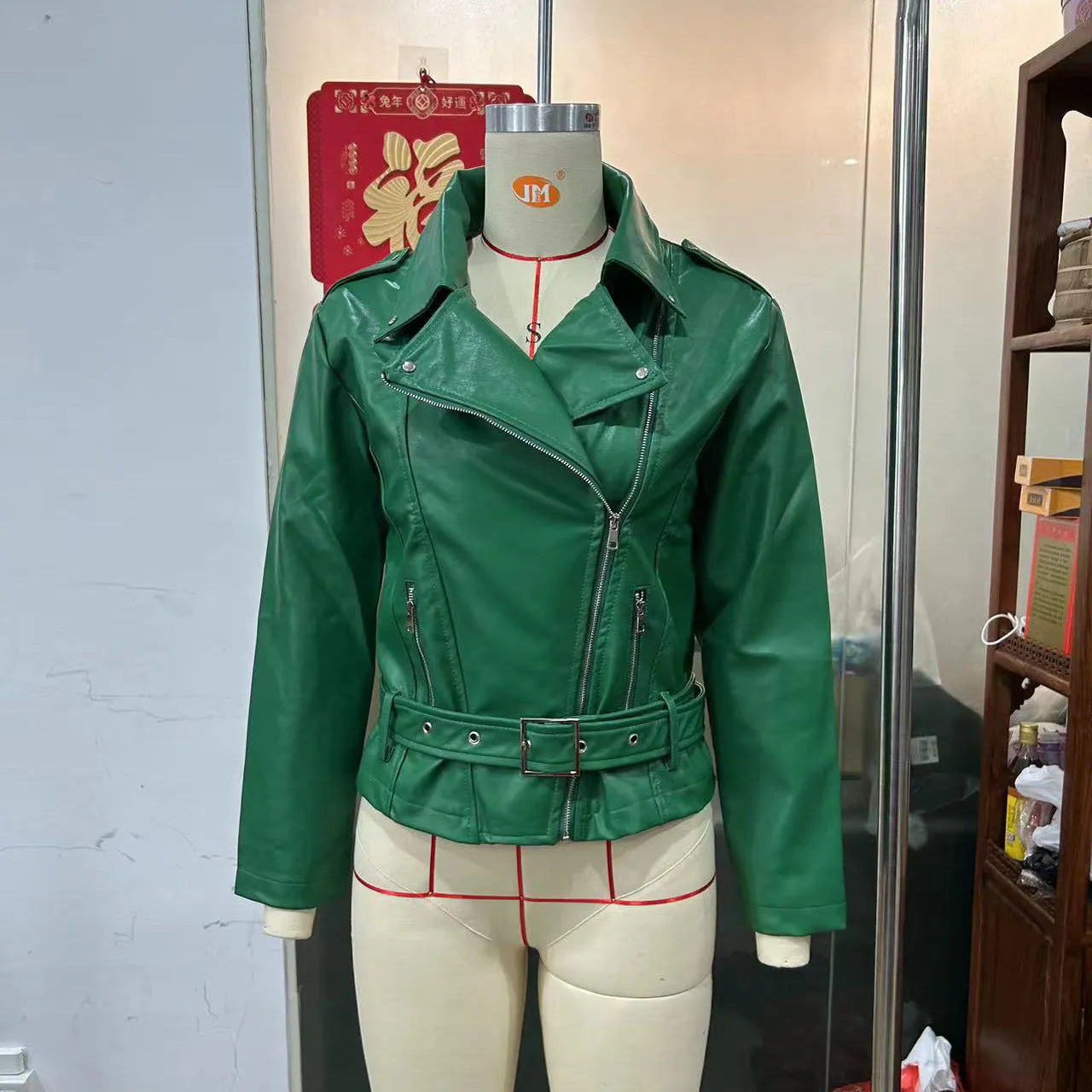A black punk-style jacket with a lapel, short belt, and Peter Pan collar on a hanger.