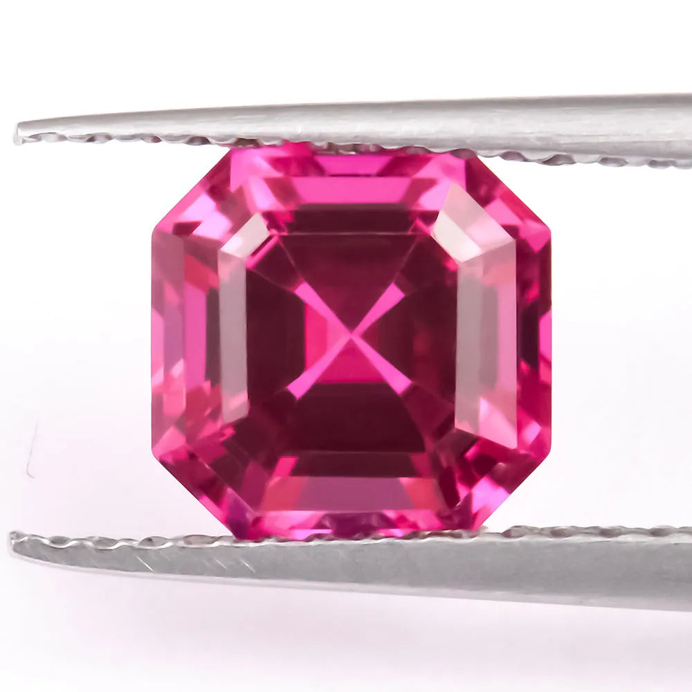 Loose cultivated pigeon blood red ruby gemstone in a princess cut on a grey background.