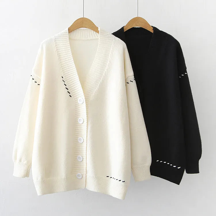 Women's loose fit black knitted cardigan coat with long sleeves on a hanger.