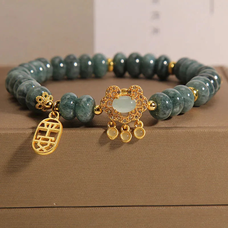 Close-up of a women's bracelet with emerald green jade abacus beads and a metallic safety lock clasp.