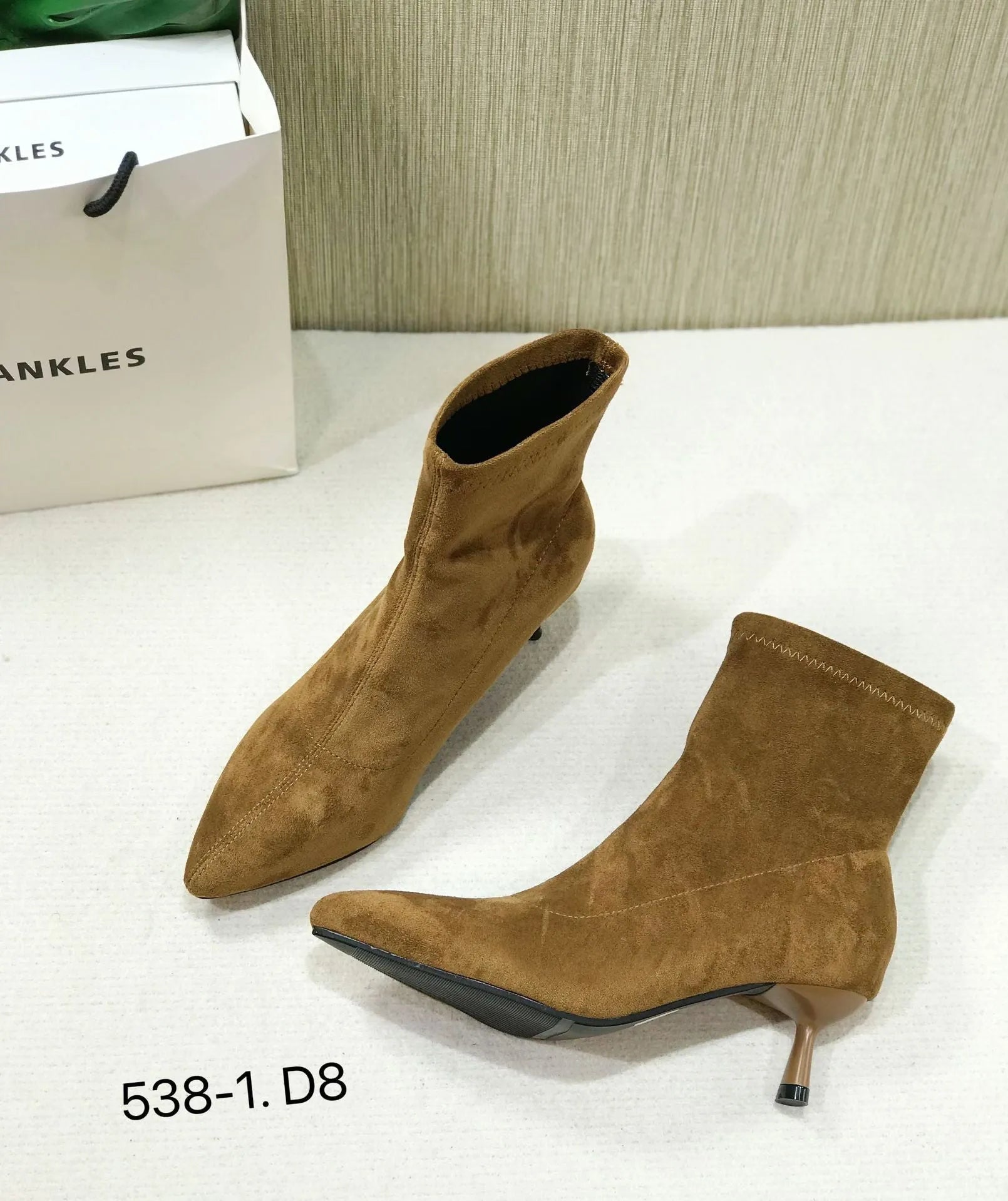 Black pointed toe women's ankle boots with stiletto heels on a neutral background.