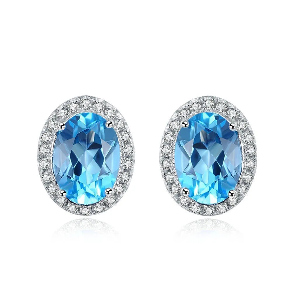 Four-piece 925 sterling silver jewellery set with blue topaz gemstones in a geometric design, showing earrings, ring, pendant and necklace.