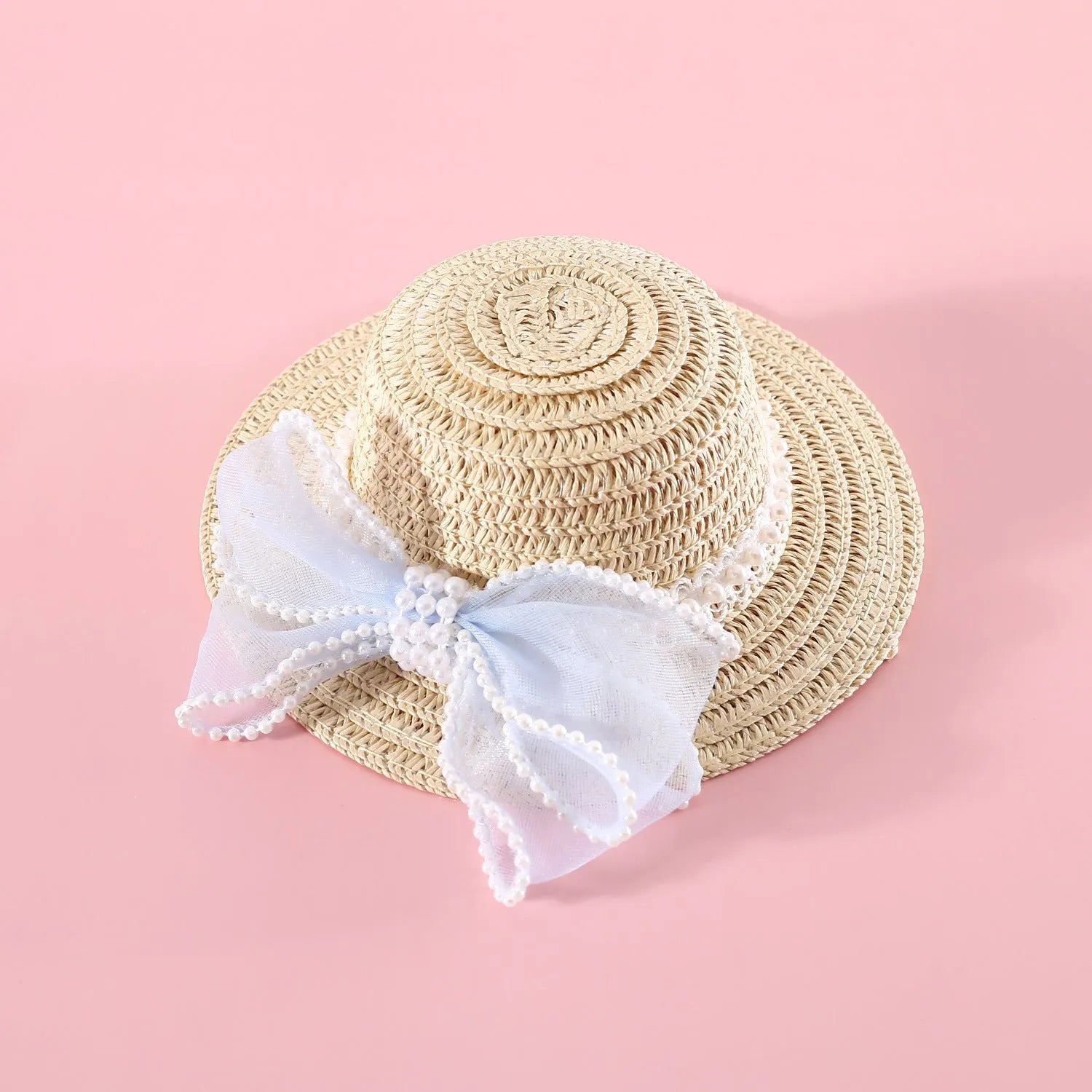 Cat wearing a woven straw hat with a pearl bow decoration in a princess style.