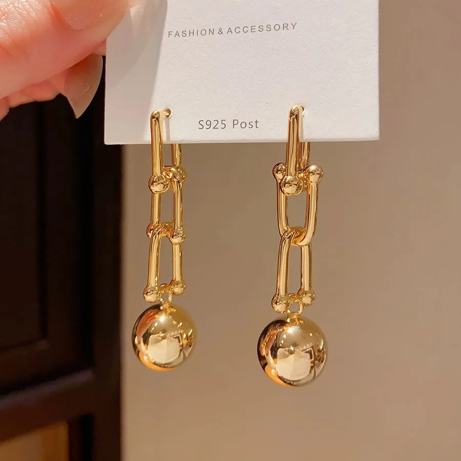 Gold long fringe earrings on display showing geometric line design and electroplated metal finish