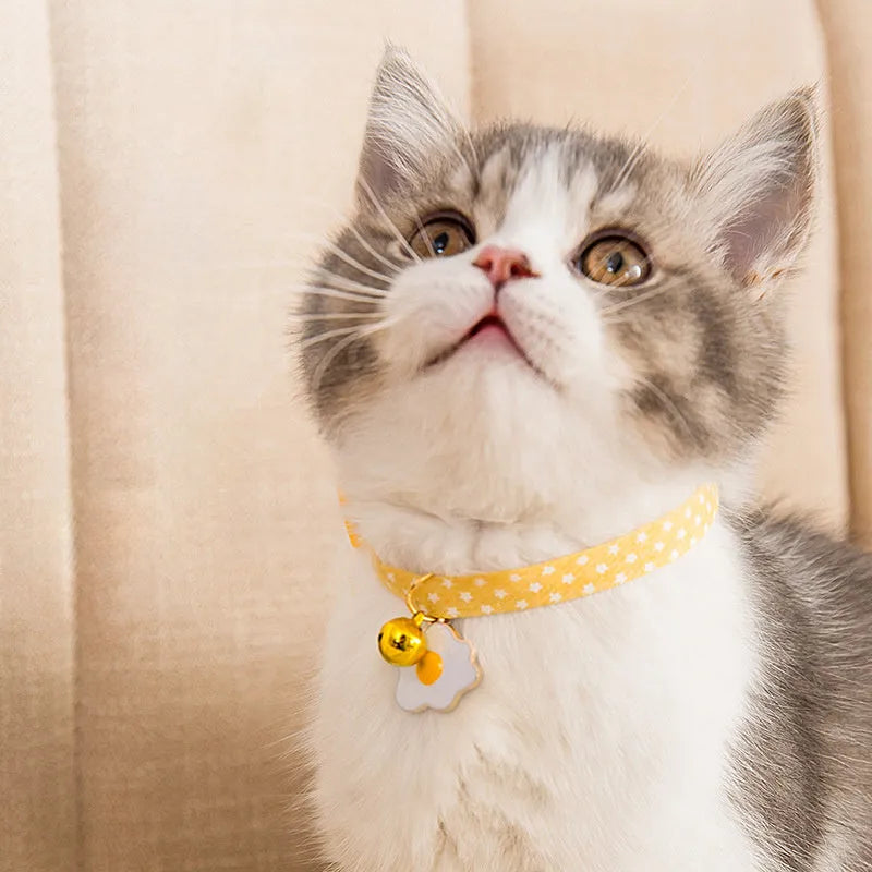 Green adjustable pet collar with a metal bell pendant and a matching bow tie on a white background.