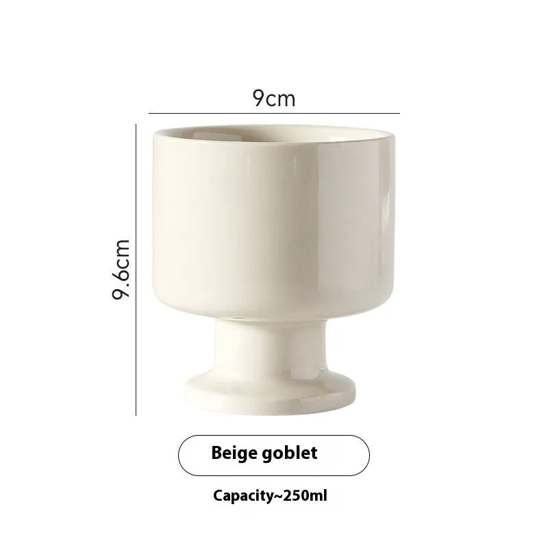 Hand-pinched irregularly shaped ceramic mug in a solid colour, shown on a table.