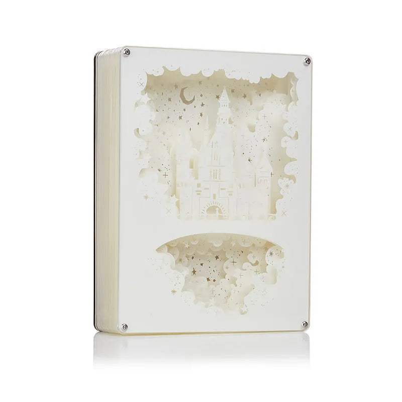 Modern romantic night light with three-dimensional paper carving design and remote control on a bedside table.